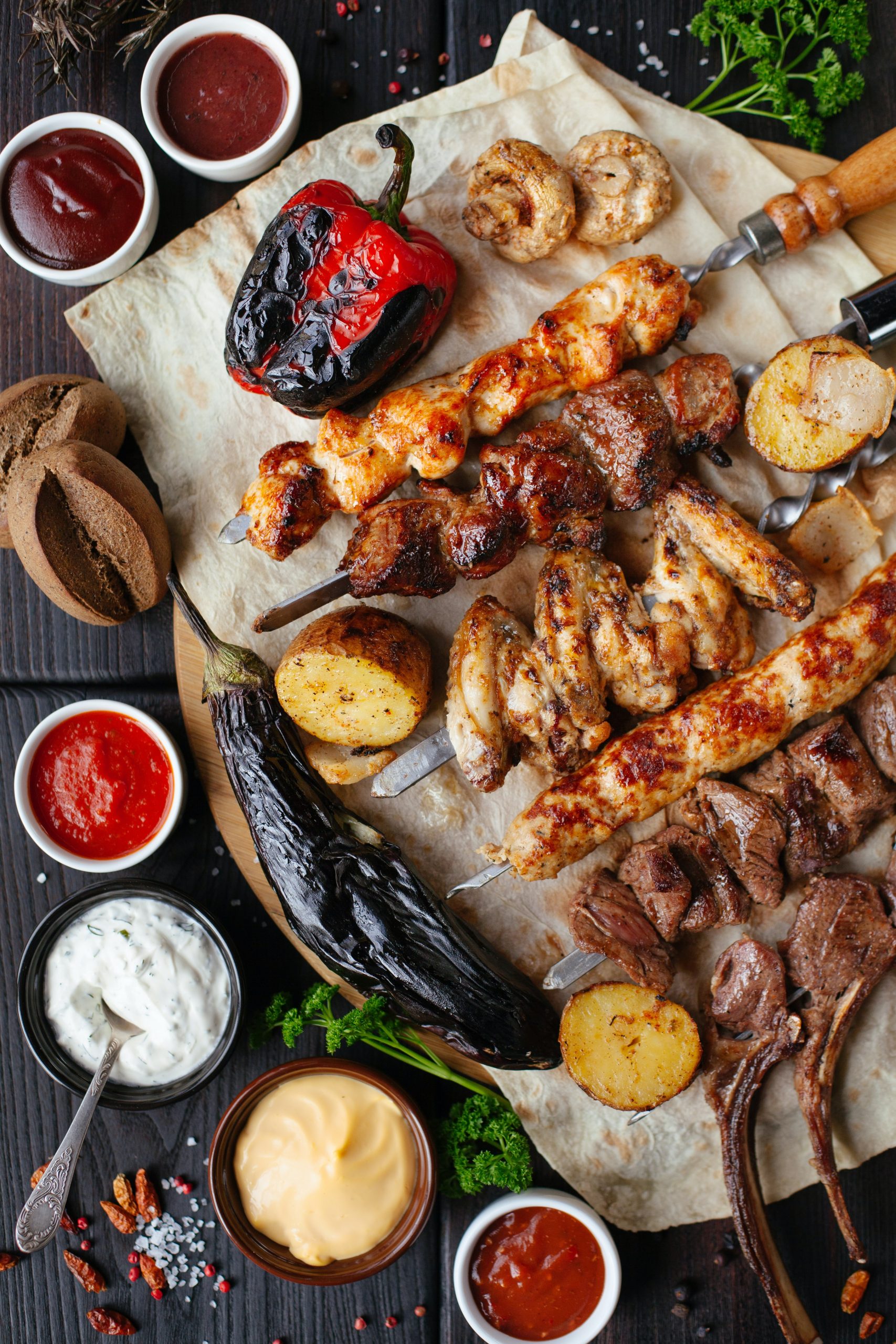 Table remplie de grillades, avec des brochettes de viande blanche, légumes, ...